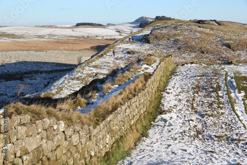 Image of Hadrian's Wall taken in an easterly direction showing walkers contending with the steep and icy footpath in the Steel Rigg area near Sycamore gap