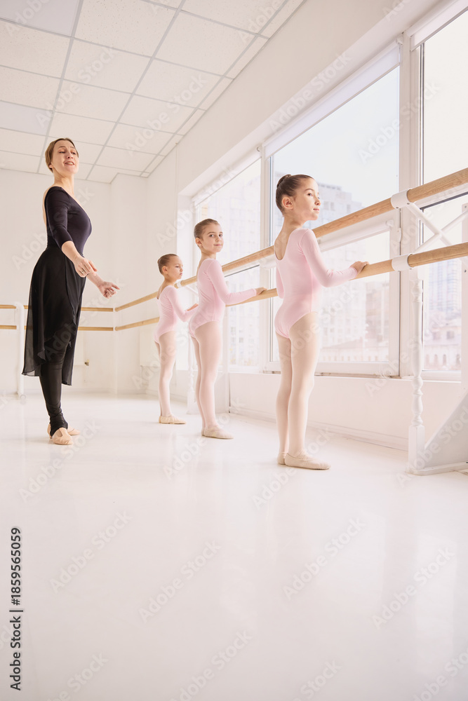 Fototapeta premium Children ballet class focused on posture and physical training. Concept of body alignment development, movement skill education, and youth physical activity use.