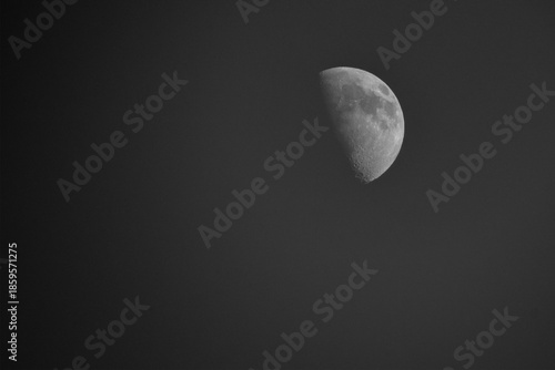 A detailed monochrome moon in a waxing gibbous phase is positioned in the upper right corner of a vast black sky.