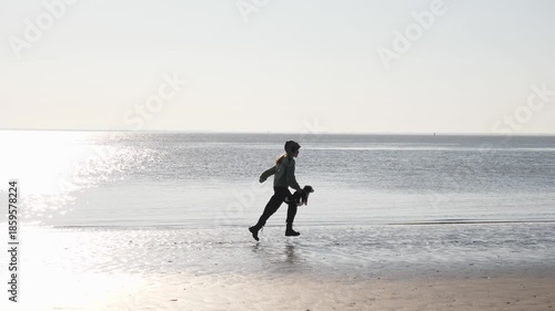 Happy teenager kid girl runs along the Atlantic Ocean beach in western France on sunny winter day