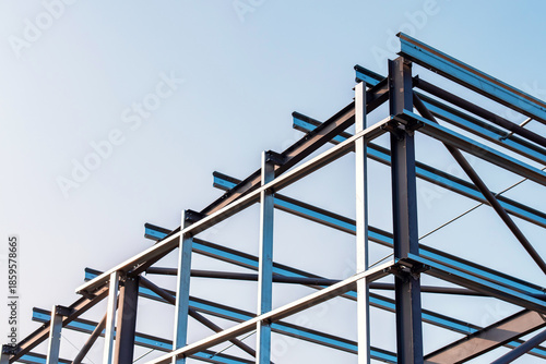 Framework of  modern steel frame building erected against a clear sky during the day showcasing steel construction and architectural design