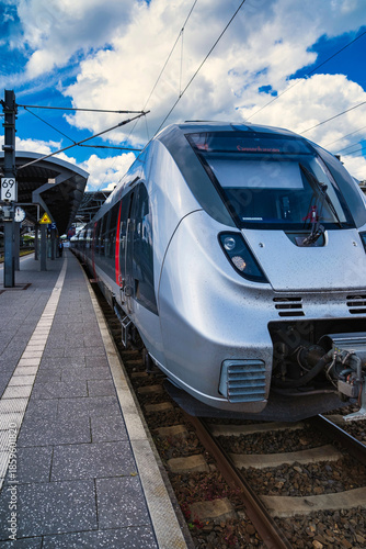 Refined locomotive at platform, contemporary transportation scene with passengers and signage present