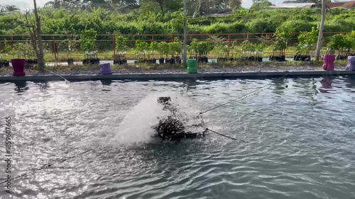 Paddle Wheel Aerator Splashing Water in Fish Pond with Mountain Background