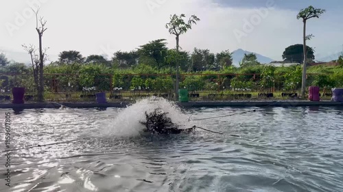 Paddle Wheel Aerator Splashing Water in Fish Pond with Mountain Background