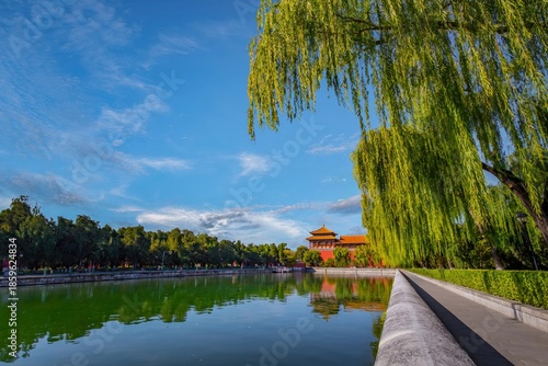Scenic view of Beijing's Forbidden City with the Tongzi River and lush willows under a clear blue sky, capturing the essence of Chinese architecture.