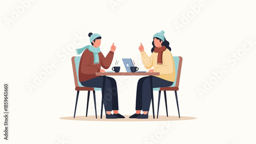Two women engaged in a friendly conversation over coffee using digital devices in winter clothing
