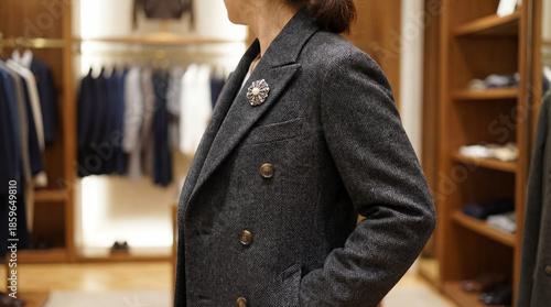 Woman in tailored gray blazer posing in modern clothing store  