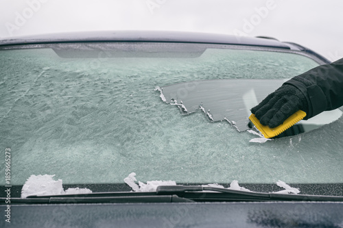 Hand kratzt Eis von Autoscheibe – Symbol für Winter, Kälte und Autofahren im Winter