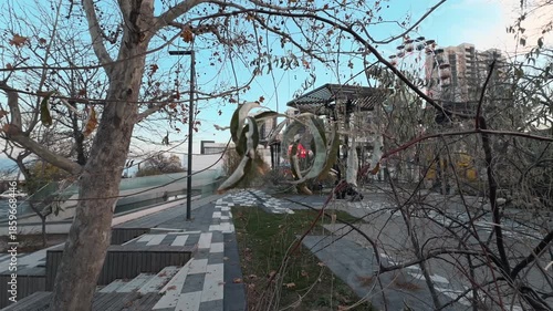 Wallpaper Mural The scene transitions from a close-up shot of a dry leaf on a tree branch to a wide shot of a city park. An autumn day outdoors. Nature and people Torontodigital.ca