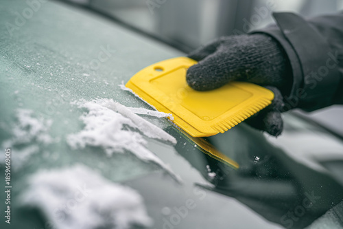 Hand kratzt Eis von Autoscheibe – Symbol für Winter, Kälte und Autofahren im Winter