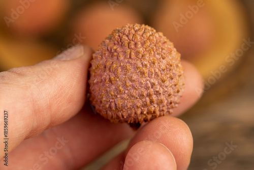 Tableau sur toile take ripe red lychees scattered on a wooden table, ripe red-skinned lychee fruit
