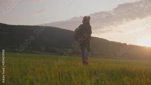 Silhouette of traveler on hill during dusk, Traveler pauses atop hill to watch sunset glow over valley