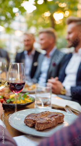 Grilled steak dinner with wine glasses and men at outdoor restaurant table