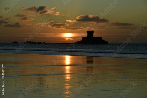 19th century Rocco tower, Jersey, U.K. Coastal Winter sunset on the beach with military fort in silhouette.