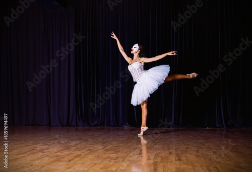 Dance performer practices ballet routine on stage during a rehearsal in a dark theater
