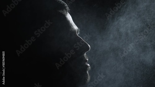 Male Face Silhouette with Refreshing Water Droplets from Spray in Darkness