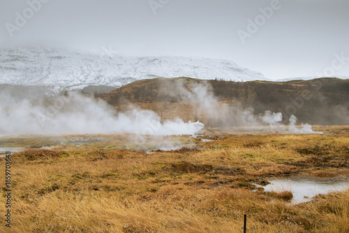 Dramatic landscape of steam rising from geothermal hot springs in Iceland.
