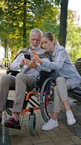Disabled senior man watches social networks with daughter