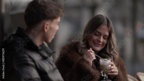 A couple enjoys coffee at an outdoor in Paris France The woman stirs her drink with a spoon and smiles The scene depicts a romantic date in a European city showcasing a lifestyle love and travel conce