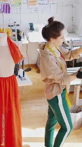 Fashion business. Young woman fashion designer making individual look, choosing clothes from rack at studio, top view