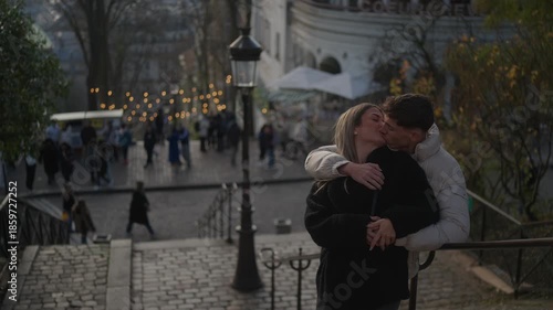 A romantic couple embraces in Montmartre Paris The man hugs the woman on cobblestone steps overlooking the cityscape The scene captures love and affection during a European vacation in France.