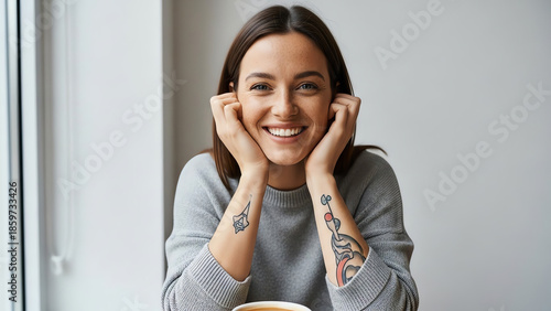 Young woman smiling while sitting indoors with coffee cup  