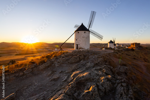 Consuegra windmills and castle glowing at sunset in La Mancha