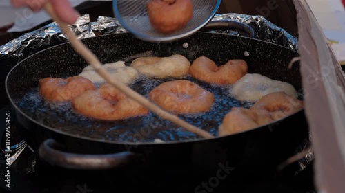 Close up of golden zeppole cooking on traditional pan