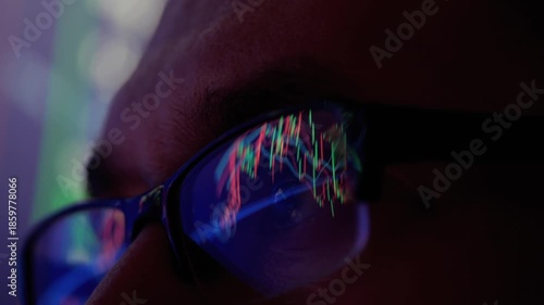 Trader Wearing Glasses Working on Laptop Computer. Candlestick Charts and Financial Graphs Reflecting in His Lenses. Screen with Stock Market Charts Data Analysis Reflection. Broker Trading Online