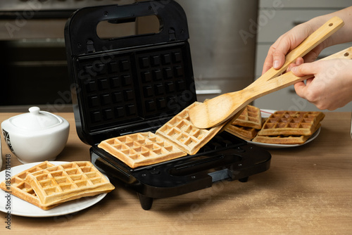 Taking Out Hot Golden-Brown Waffles from an Electric Maker in a Home Kitchen.