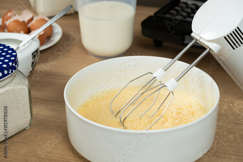 The process of beating eggs with sugar with a mixer, close-up, making the dough.