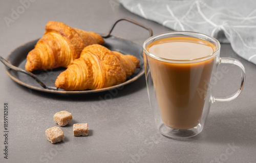 Warm croissants and a cup of coffee on a table in a simple kitchen setting in the morning