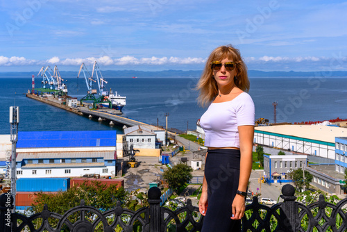 Woman enjoying a sunny day by the harbor with beautiful sea views and ships nearby