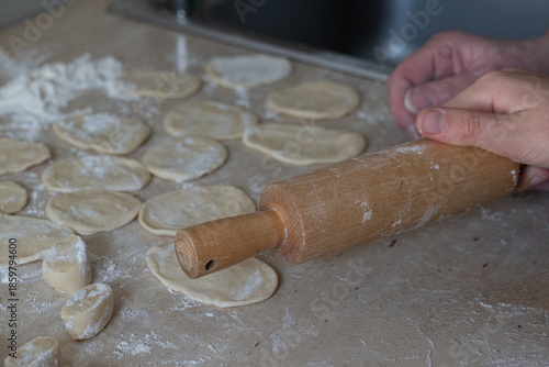 Hands of an older woman and child making dumplings together in a home kitchen. Warm family moment with homemade food, selective focus, and cozy cooking with grandma atmosphere.