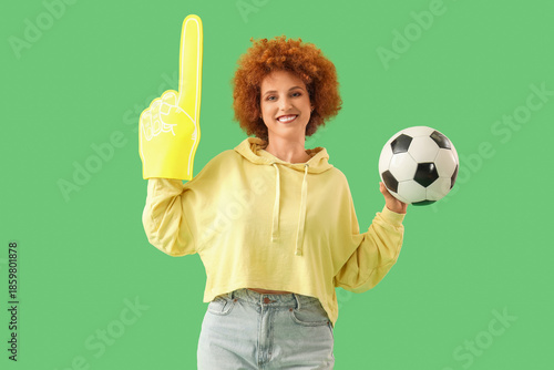 Female soccer fan with foam hand and ball on green background