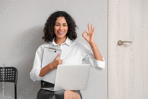 Schilderij op canvas Female African-American job applicant with laptop showing OK in hall