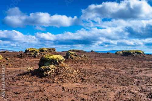 Eroded peatland landscape with exposed dark soil and isolated peat ‘islands’ under a bright blue sky