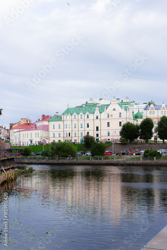 Calm Waters Mirror Colorful Architecture, Gentle Ripples Over Tranquil Waters Beneath Overcast Sky