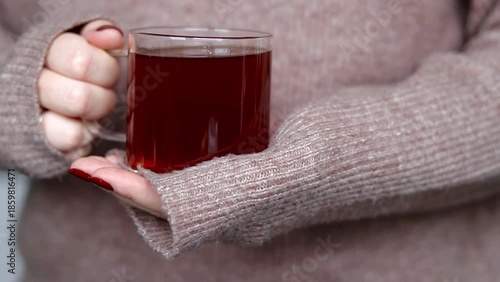 Close up of female hand holding a glass cup with hot tea
