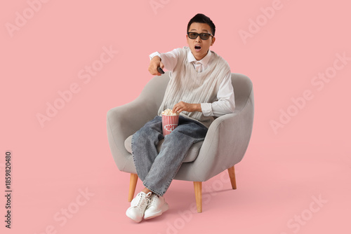 Young Asian man with TV rem...