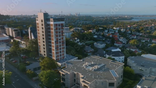 Aerial view of a residential building in Remuera, Auckland, New Zealand, with the city skyline in the background. The scene showcases urban living and architecture in a scenic setting.