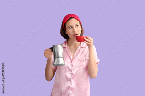 Beautiful young shocked woman in pajamas with cezve and cup of coffee on purp...