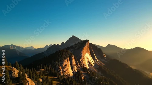 Mountain range silhouette against sunrise sky with sun rays and atmospheric perspective