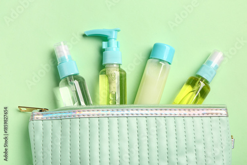 Fotografija Bag with set of travel cosmetic products on green background