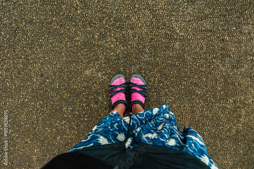 Person standing on abrasive ground wearing sandals with pink socks