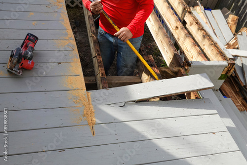 Handyman is seen removing an old floor board during a deck demolition
