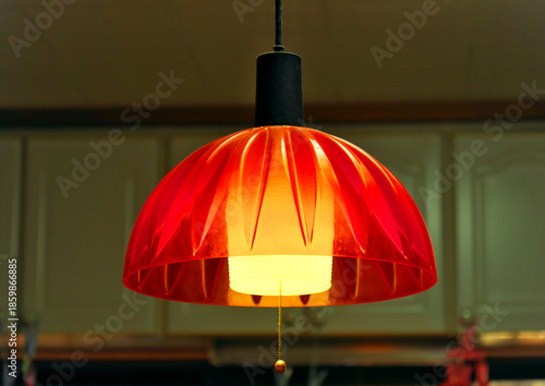 暗がりに浮かぶレトロなオレンジ色の照明・昭和の雰囲気を残すペンダントライトの灯り・静かな夜の日本の家庭の情景・ノスタルジックなムード