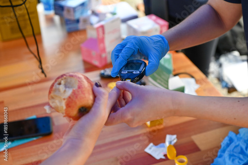 Nurse pricking a patient's finger to perform a blood glucose test.