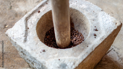 Grinding coffee in the traditional way using a stove made of stone (Indonesians call it lumpang)