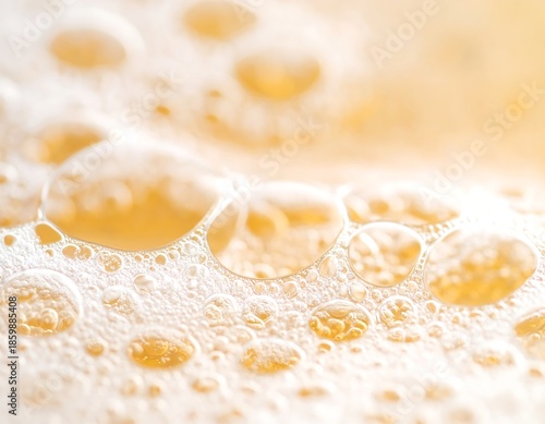 Close-up view of frothy, bubbly liquid, with varying sizes of clear, reflective spheres. Soft focus, bright highlights